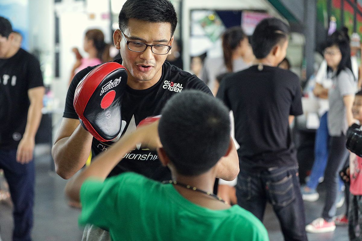 Thai MMA fighter Shannon Wiratchai holds pads for a child