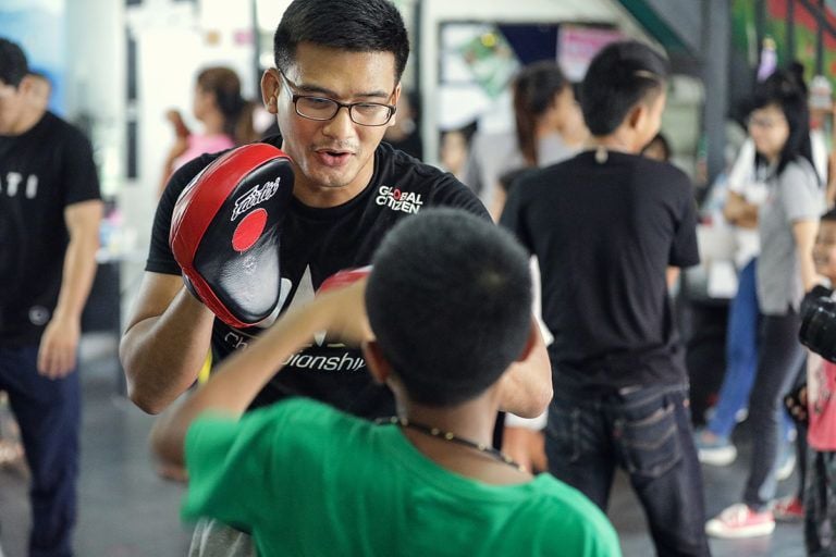Thai MMA fighter Shannon Wiratchai holds pads for a child