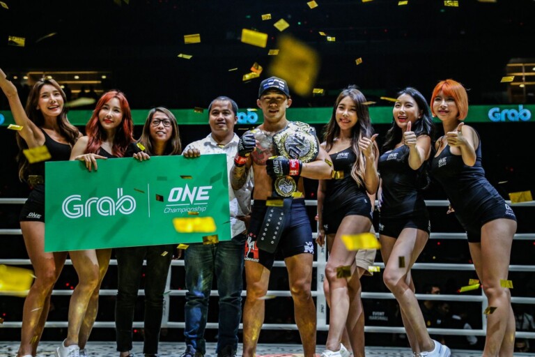 Martin Nguyen, ONE Featherweight World Champion, holds his World Title belt with the ONE ring girls.