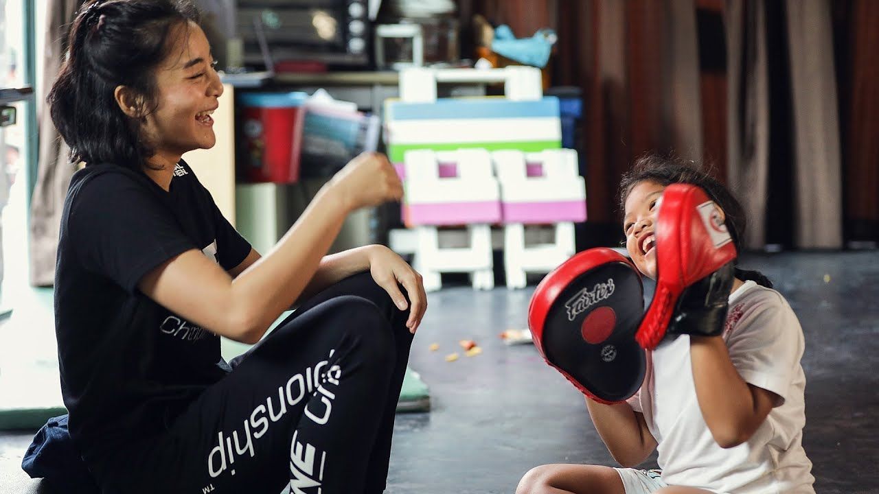 Thai MMA fighter Rika Ishige and a child holds focus mitts