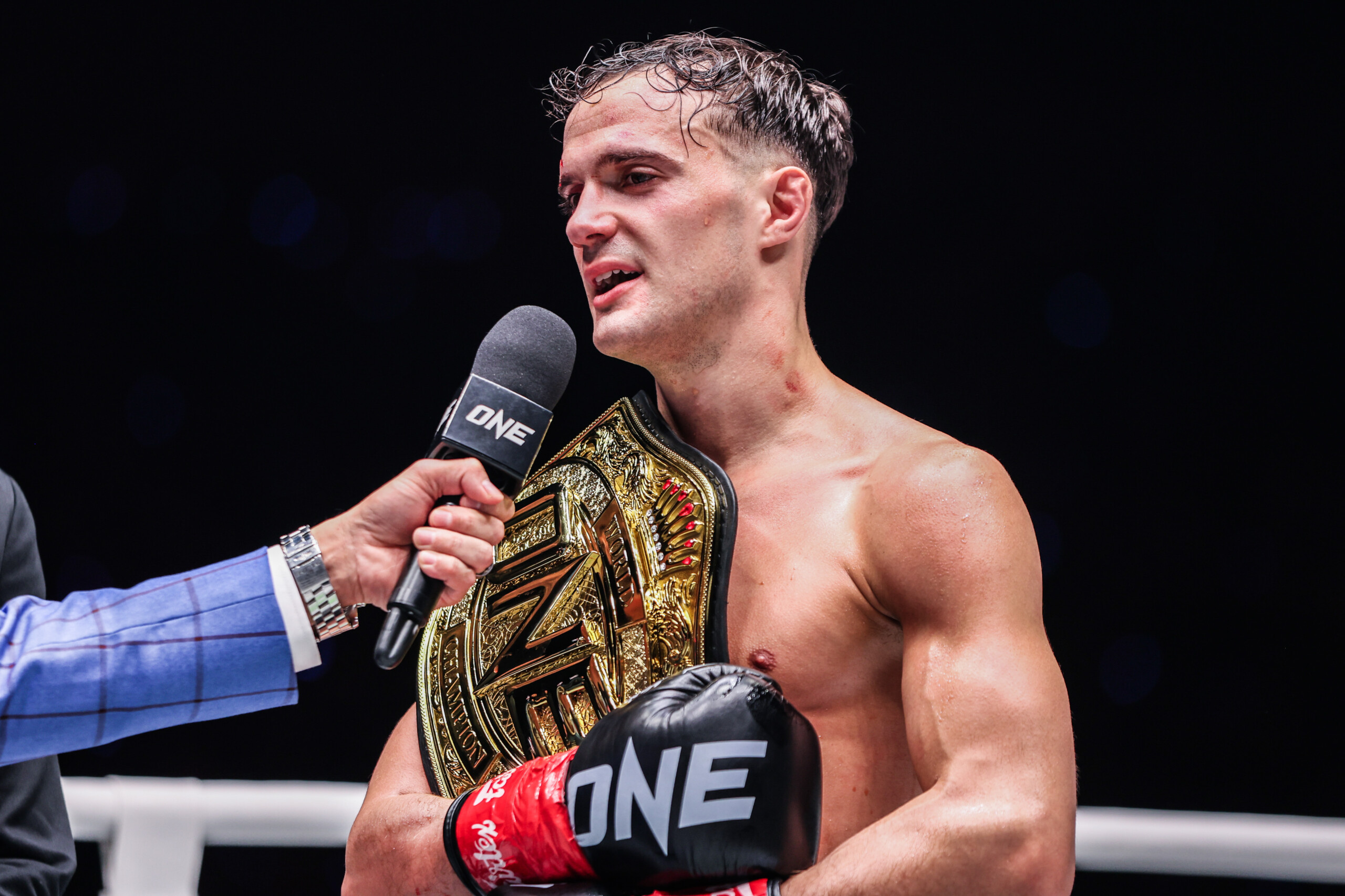 Kickboxing champ Jonathan Di Bella talks into the microphone following his win