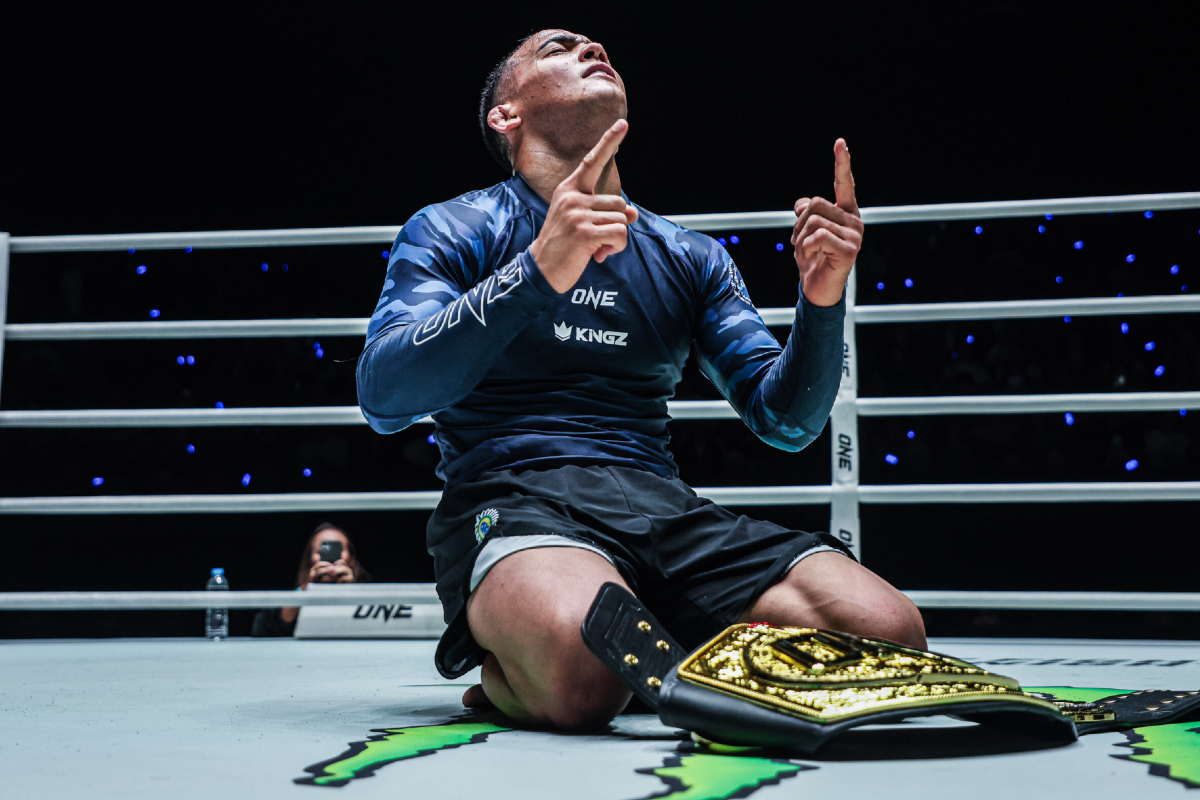 Diogo Reis looks up to the sky with the ONE Championship belt in front of him