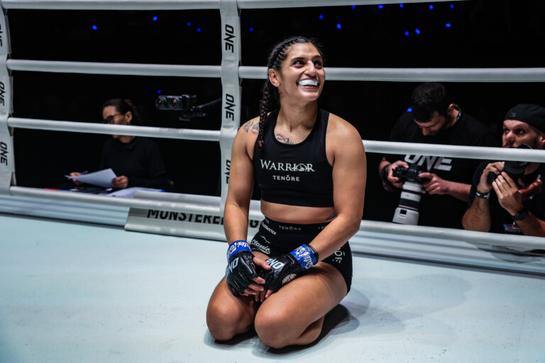 Natalie Salcedo kneels and smiles in the ring