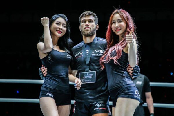 Finnish mixed martial arts star Aleksi Toivonen with the ring girls and his winner's medal in July 2019