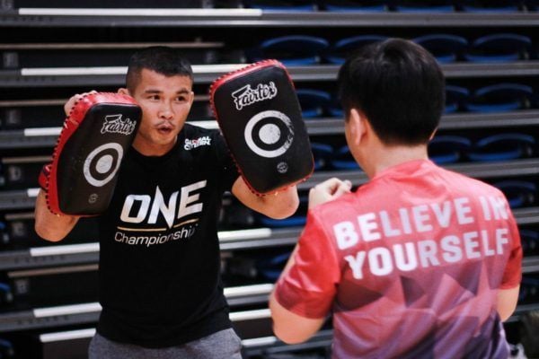 ONE Bantamweight Muay Thai World Champion Nong-O Gaiyanghadao holds kick pads for a Singaporean youth