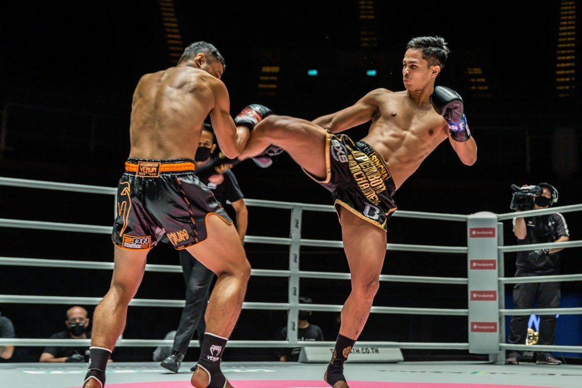 Thai kickboxer Superbon whips a kick at Sitthichai Sitsongpeenong's body